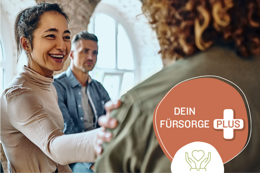 Eine sympathisch lächelnde Frau legt ihre Hand auf die Schulter einer anderen Person. Die Geste strahlt Mitgefühl aus. Im Bild ist das Textelement „dein Fürsorge Plus“ in einem roten Kreis mit einem Plus-Symbol.